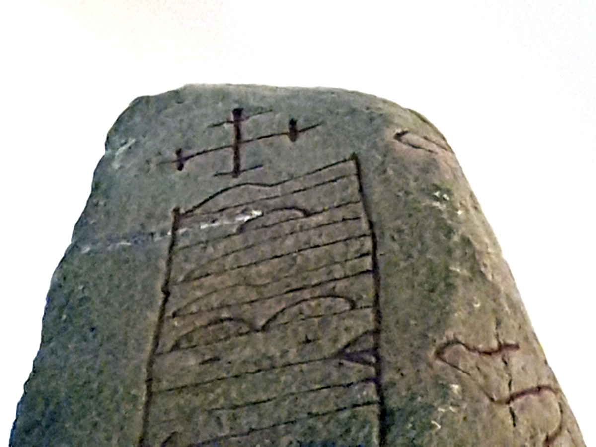 A crossed crucifix at the top of the Lundagård runestone of the same type that can be found at Harald Bluetooth's coins